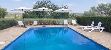 Una piscina al aire libre de temporada, sombrillas