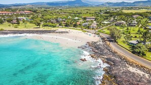 A coastal resort with a beach, clear turquoise waters, and a backdrop of mountains. - Summer Deal Poipu Beach Condo 5 Min Walk to Ocean Pools and Hot Tub (KOLOA)
