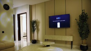 Uma sala de estar moderna com uma TV de tela plana exibindo uma mensagem, um sofá, uma mesa de centro e duas plantas em vasos.