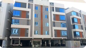 Um edifício residencial de vários andares com design arquitetônico moderno, com varandas e janelas amplas.