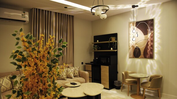 Uma sala de estar moderna com um sofá, duas mesas redondas e uma planta decorativa.