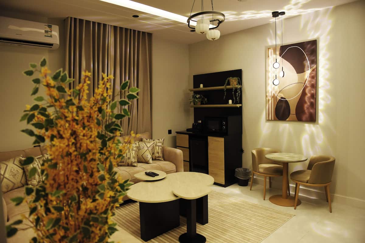 A modern living room with a sofa, two round tables, and a decorative plant.