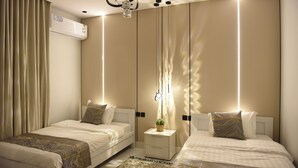 Quarto moderno com duas camas, uma mesa de cabeceira com abajur e um aparelho de ar condicionado na parede.