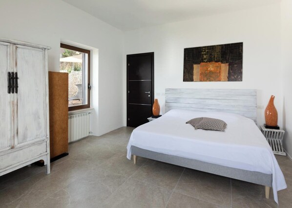 A bedroom with a large bed, a wardrobe, a door, and a window.