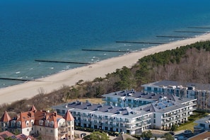 A coastal hotel with multiple buildings, a beach, and a pier.