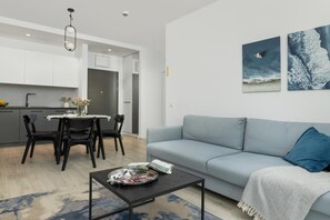 A modern living room with a grey sofa, a coffee table, and a dining area with a table and chairs.