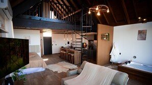 Uma sala de estar espaçosa com teto alto, escada, cozinha e uma grande janela.
