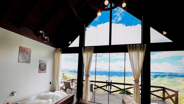 Um quarto espaçoso com uma grande janela que oferece uma vista panorâmica, um deck de madeira e uma área de estar aconchegante.