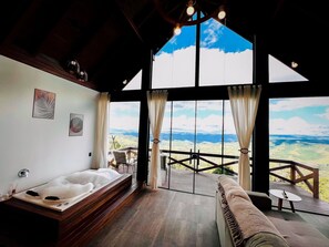 A spacious room with a large window offering a scenic view, a wooden deck, and a cozy seating area. - Chale Entre as Nuvens - Rancho Queimado (Rancho Queimado)