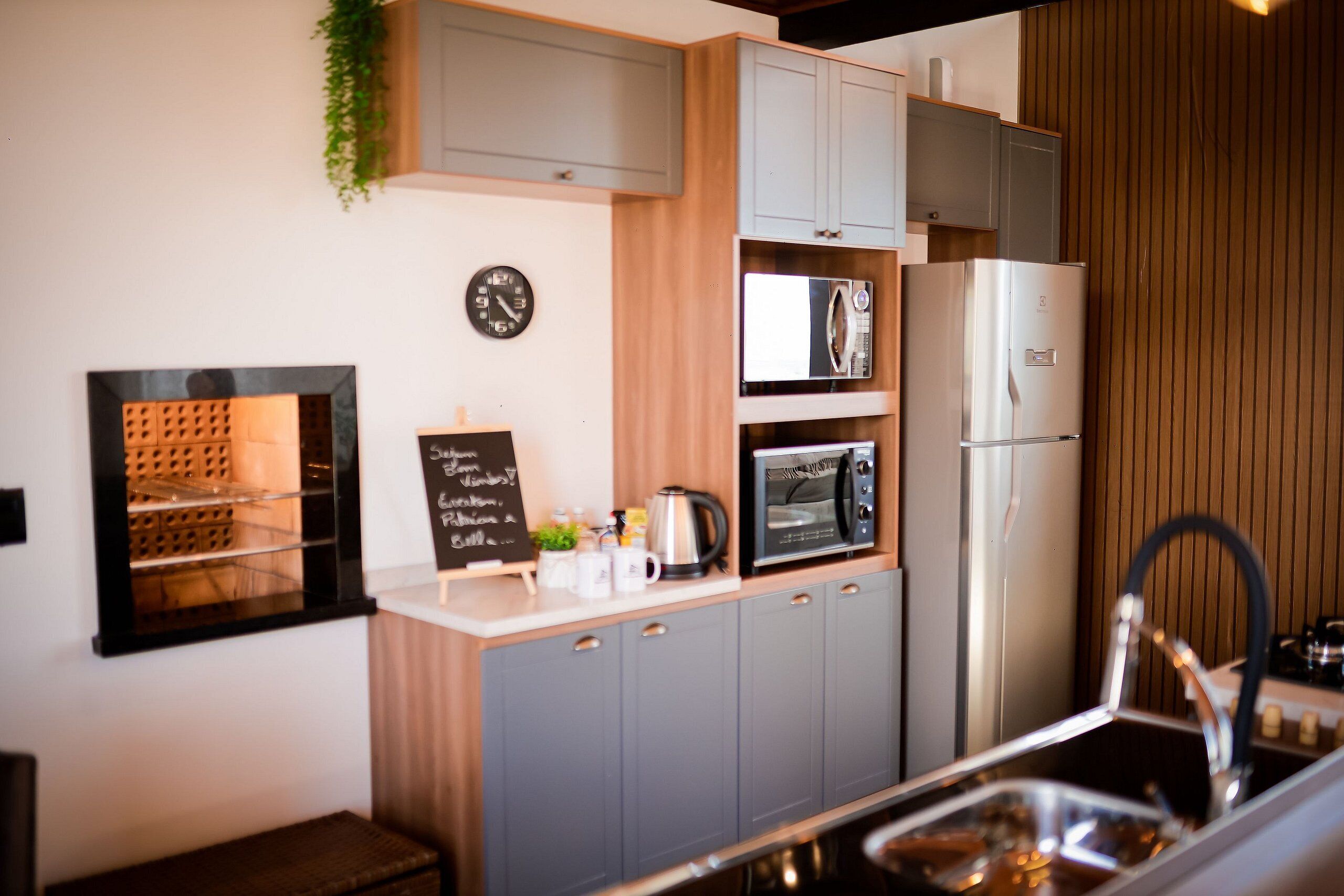 A compact kitchen with grey cabinets, a microwave, a refrigerator, and a small sink.
