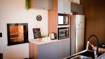A compact kitchen with grey cabinets, a microwave, a refrigerator, and a small sink.