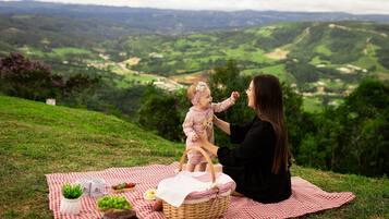 Ein Picknick auf einem grasbewachsen Hügel mit weitreichendem Blick über Hügellandschaft und Tal.