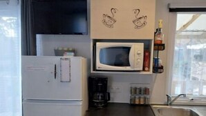 A compact kitchen with a refrigerator, microwave, coffee maker, and a sink. - Mobilhome. (Torreilles)
