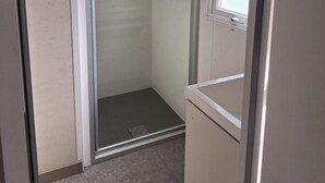 A small, enclosed shower area with a glass door, a window, and a tiled floor. - Mobilhome. (Torreilles)