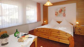 Una camera da letto con un letto in legno, comodini, un tavolo con cibo e bevande, e una finestra con tende.