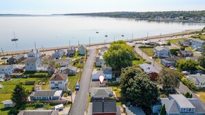 A residential area with houses, a road, and a body of water in the background.