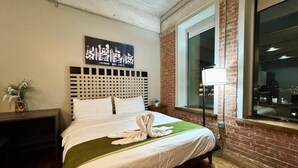 Ein Hotelzimmer mit Bett, Kopfteil, Fenster und Blick auf die Stadt.