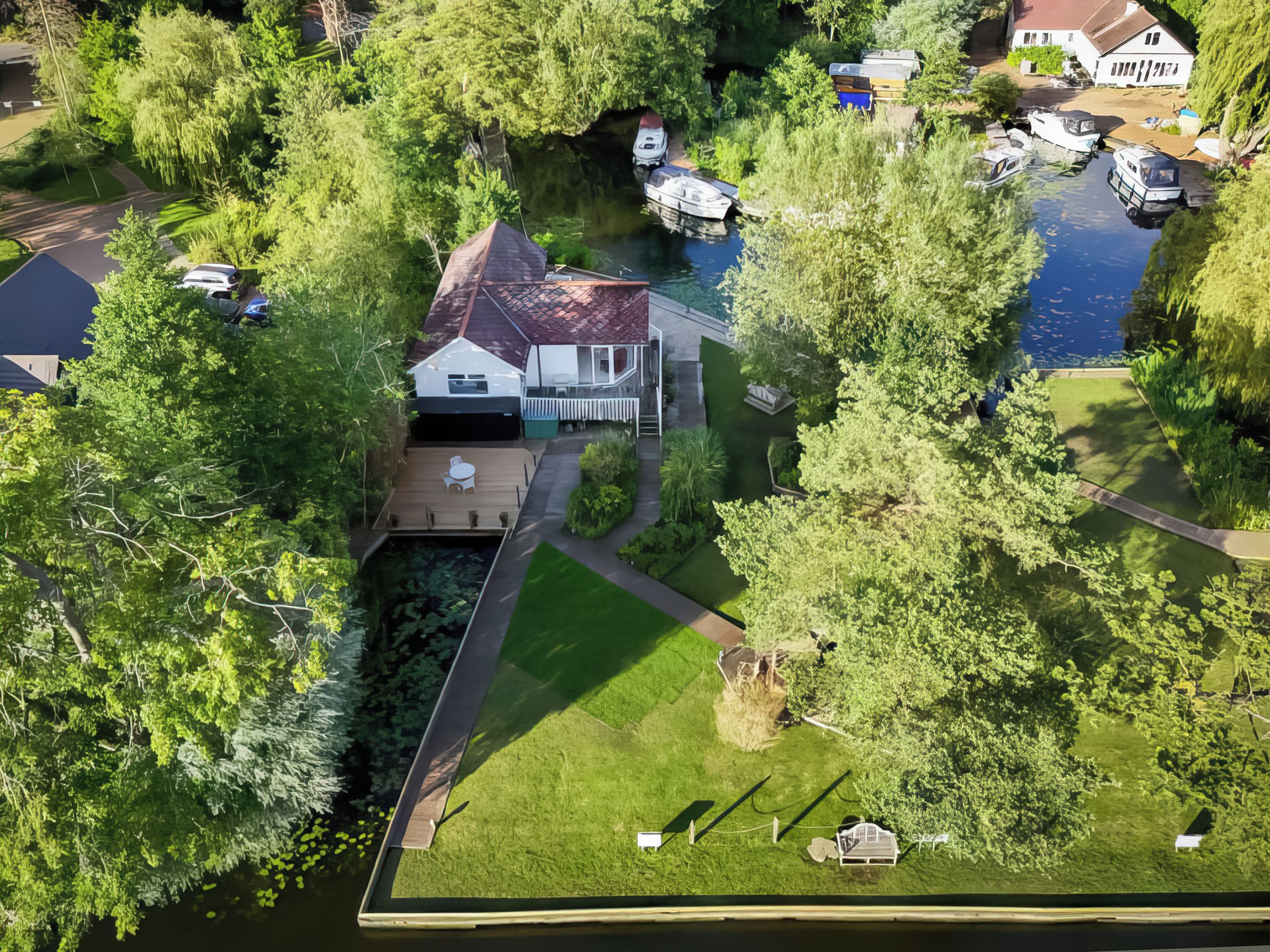 An aerial view of a residential property with a house, a dock, and boats.