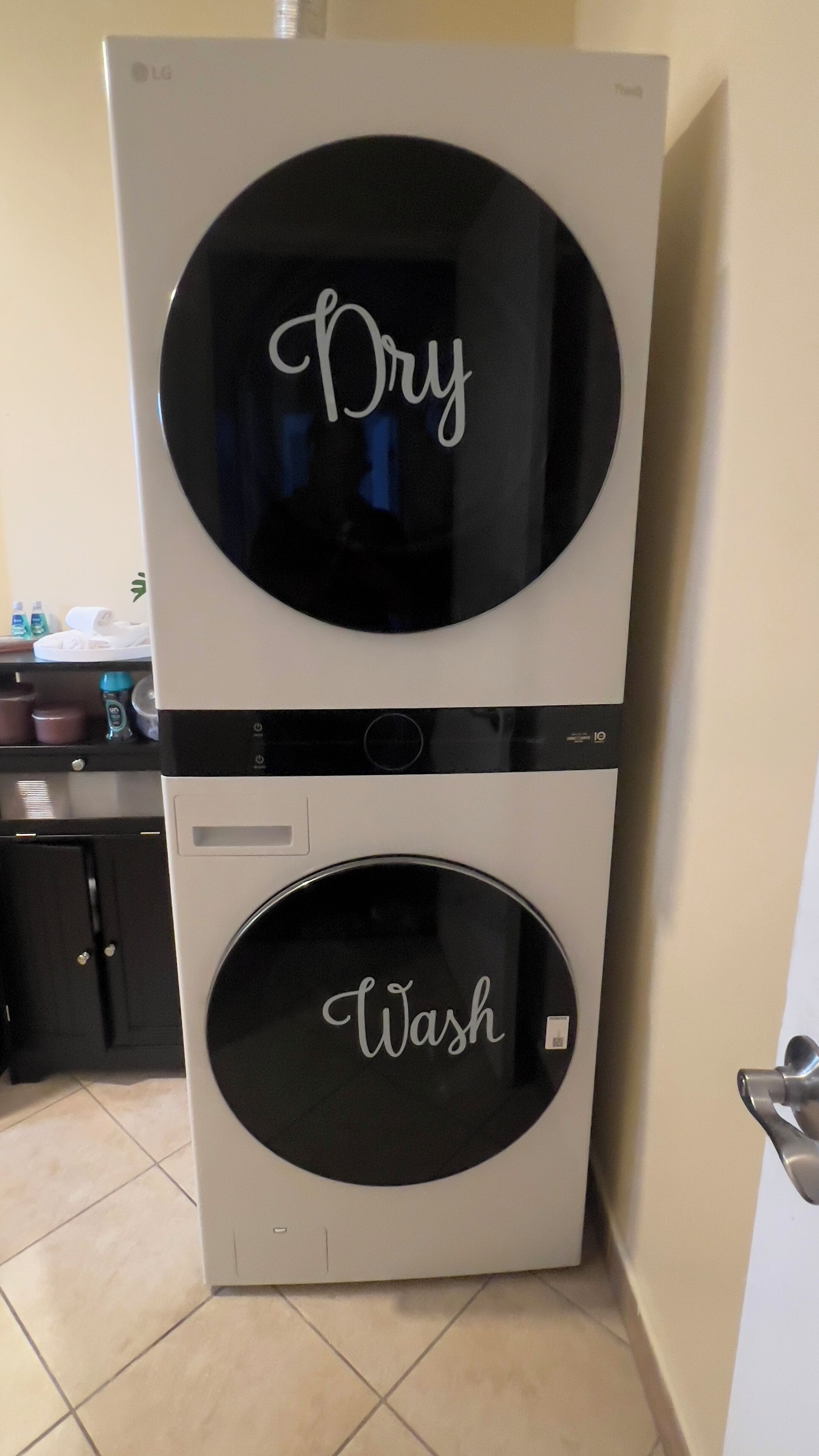 Un appareil combiné lave-linge et sèche-linge, avec les inscriptions « Séchage » et « Lavage » respectivement sur les portes du haut et du bas.