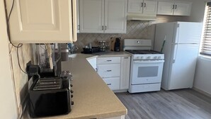 A modern kitchen with white cabinets, a black countertop, a stove, and a refrigerator.