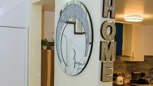 A modern kitchen with a glass display unit, a decorative mirror, and a 'HOME' sign. - Beachfront Bliss in Portmore – Stylish 1BR with Ocean Views & Modern Comfort (Portmore)