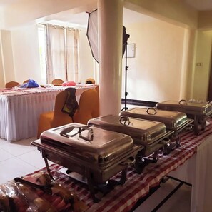 A room with a table set for a meal, a camera on a tripod, and several wheeled suitcases. - Balance Park Hotel  (Kisumu)