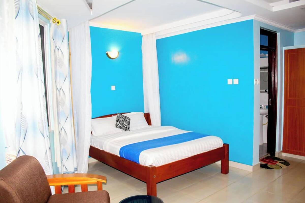 A bedroom with a wooden bed, a blue accent wall, a white ceiling, and a wooden door.