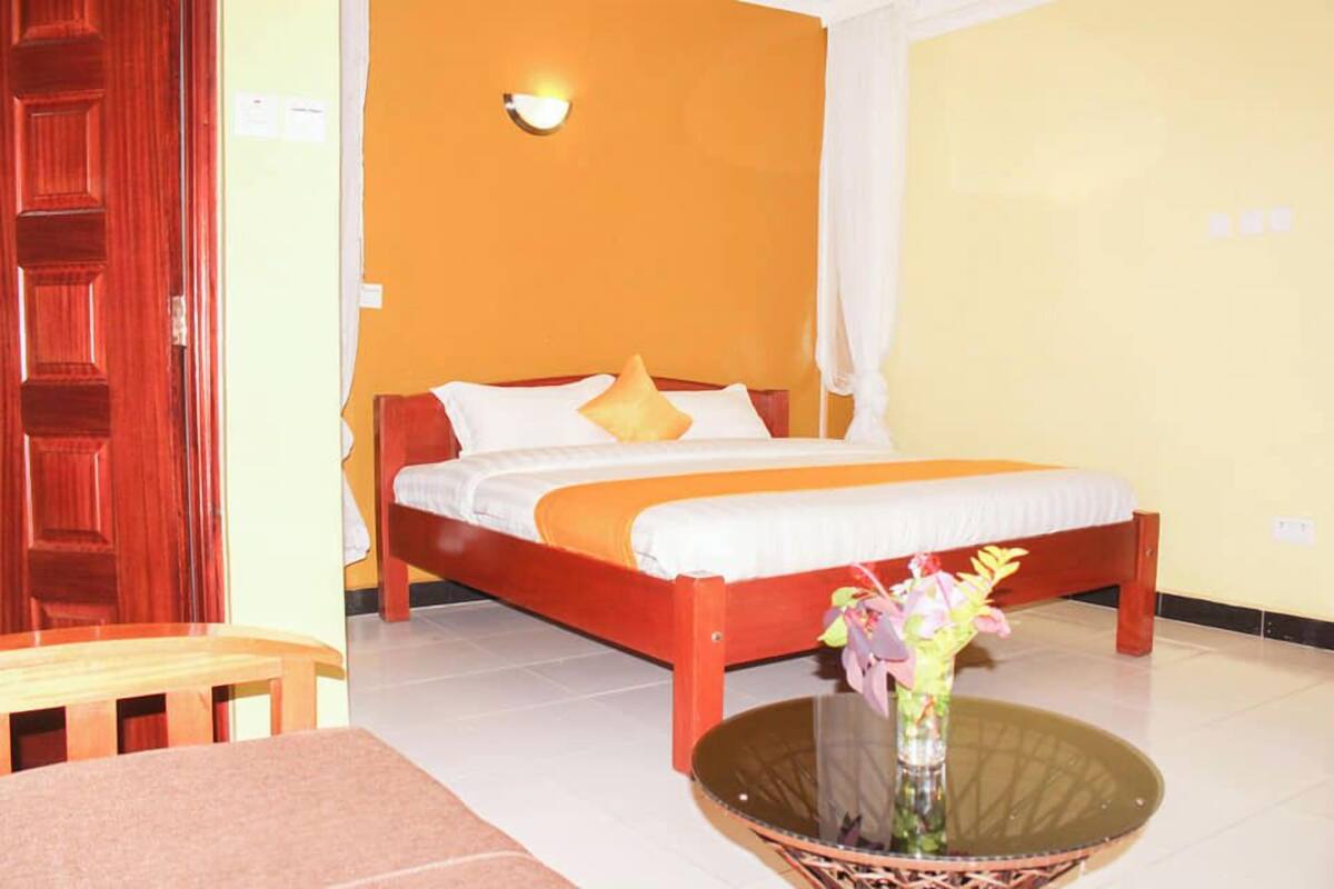 A bedroom with a bed, a bedside table, and a vase with flowers.
