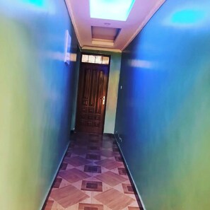 A hallway with patterned flooring and a wooden door at the end. - Balance Park Hotel  (Kisumu)