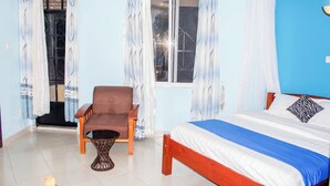 A bedroom with a bed, a chair, and a window with curtains. - Balance Park Hotel  (Kisumu)
