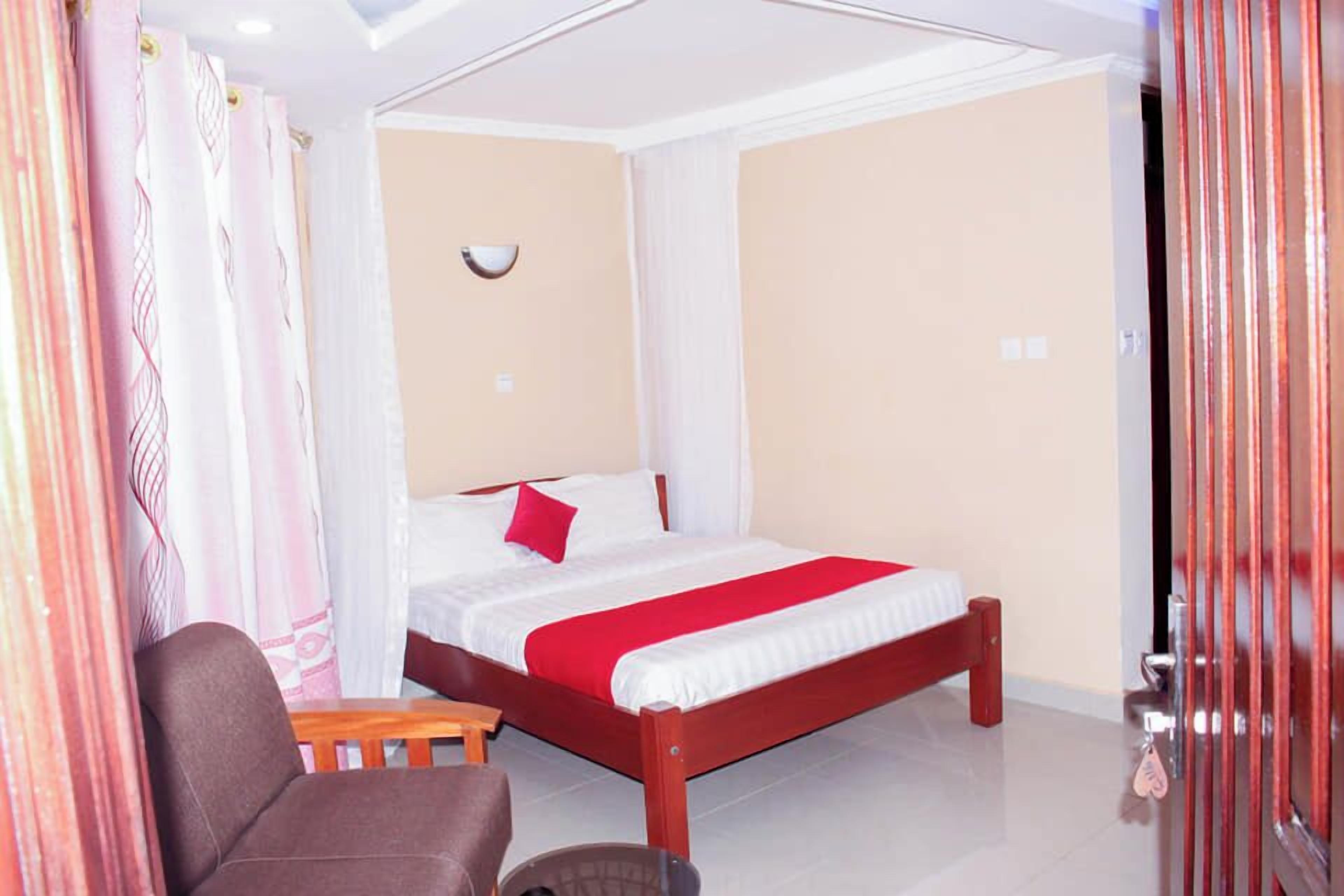 Una habitación de hotel con una cama, una silla, una mesita y una puerta con cerradura de llave.