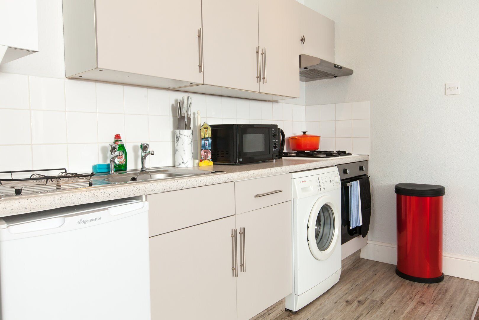 A compact kitchen with a dishwasher, microwave, stove, and washing machine.