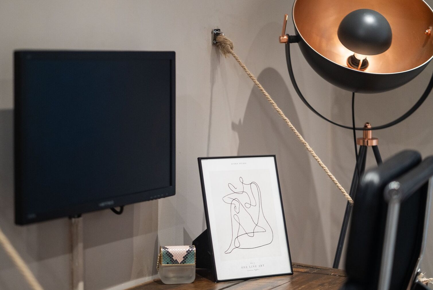 A room with a flat-screen TV, a framed abstract art piece, a lamp, and a chair.