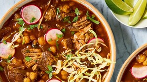 A bowl of stew with meat, beans, and radishes, garnished with herbs. - rwabs legacy motel mubende (Mubende)