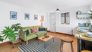 Ett modernt vardagsrum med en grön soffa, ett soffbord och en köksdel med en diskho och en arbetsbänk.
