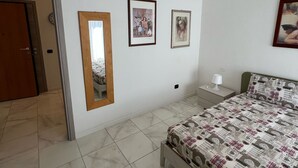 A bedroom with a bed, a nightstand, a mirror, and three framed pictures on the wall. - LITTLE HOUSE (Fossarmato)