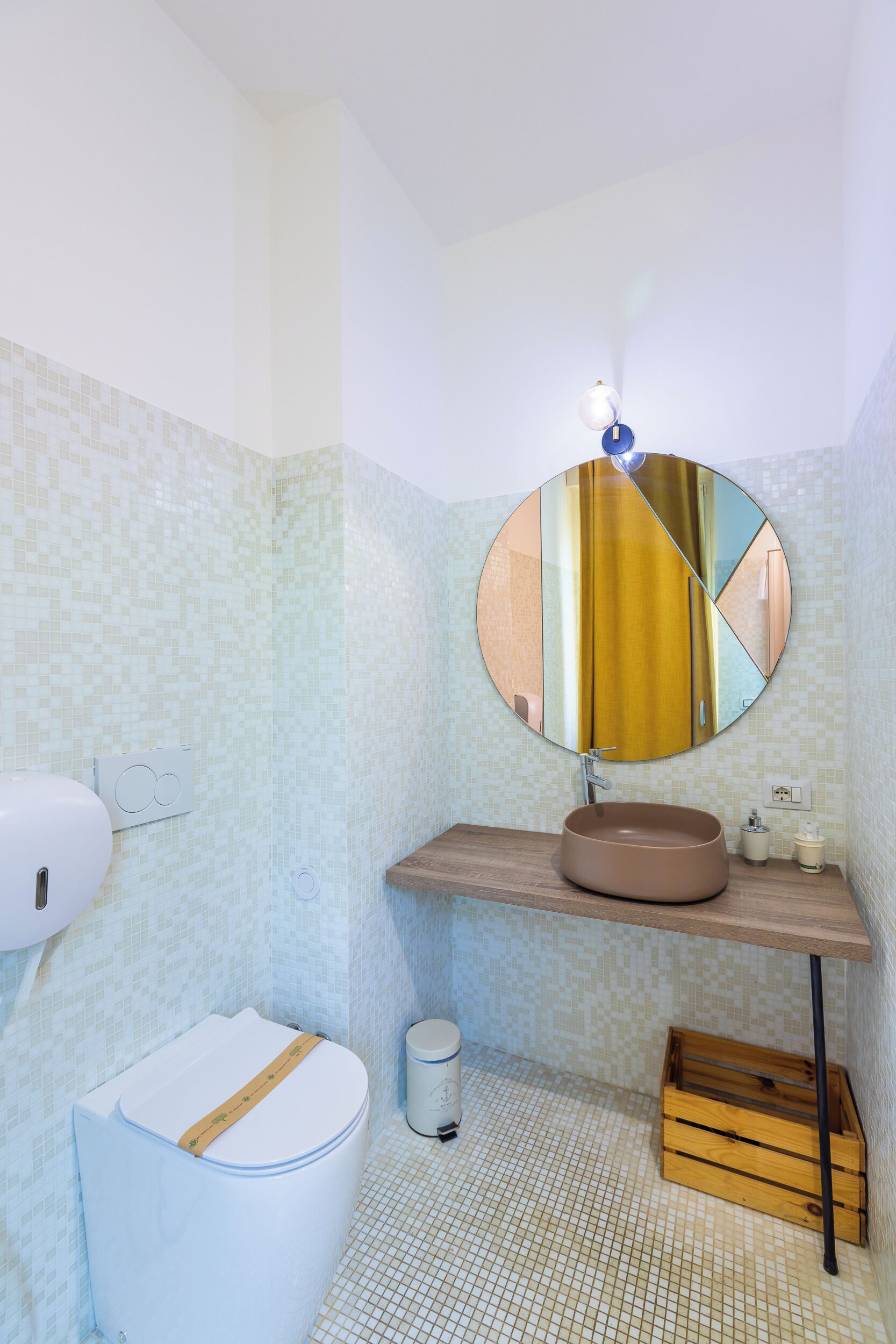 A bathroom with a toilet, sink, mirror, and storage cabinet.
