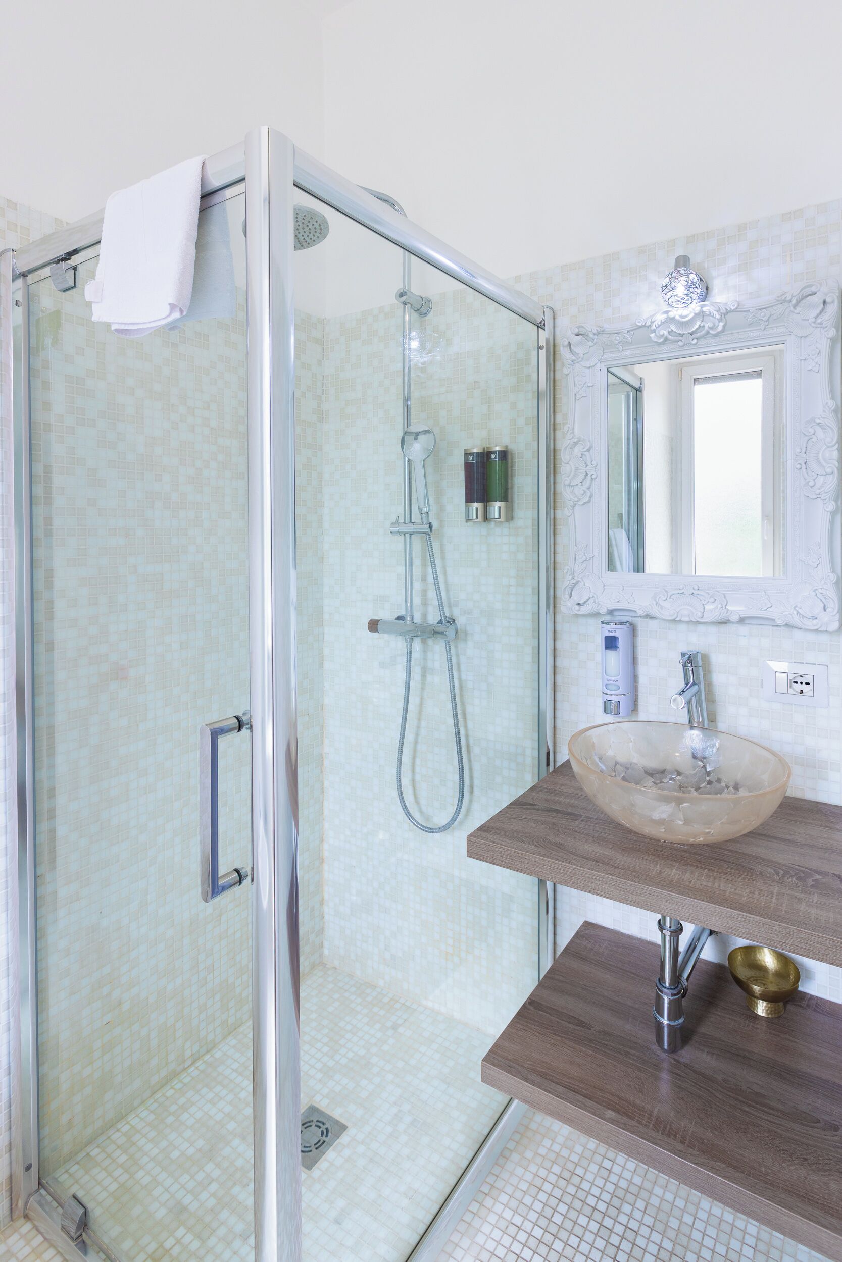 Un bagno moderno con doccia a vetro, un mobile bagno in legno e uno specchio grande.