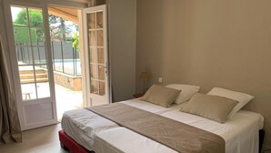 A bedroom with a bed, a sliding glass door to a patio, and a lamp on the nightstand.