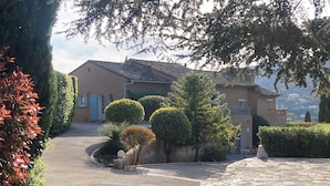 A residential area with a paved driveway leading to a house with a tiled roof.