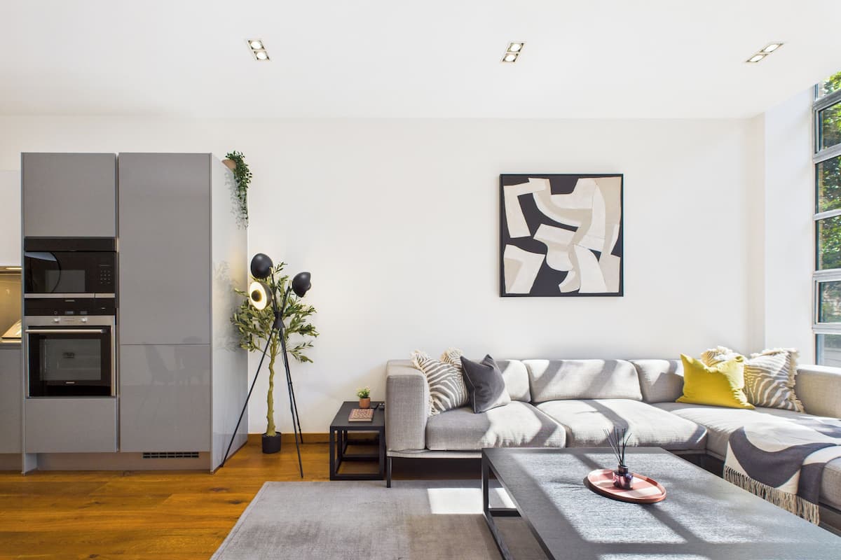 Una sala moderna con un sofá gris, una mesa de centro y una lámpara de pie.
