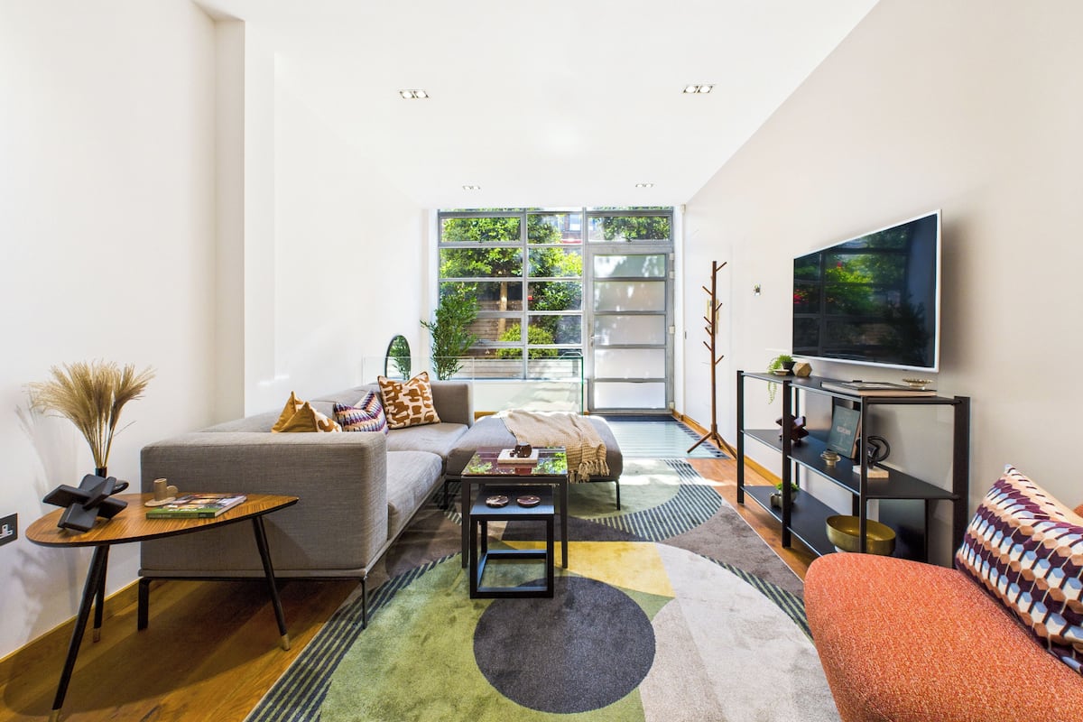 Una sala de estar moderna con sofá, mesa de centro y televisor.