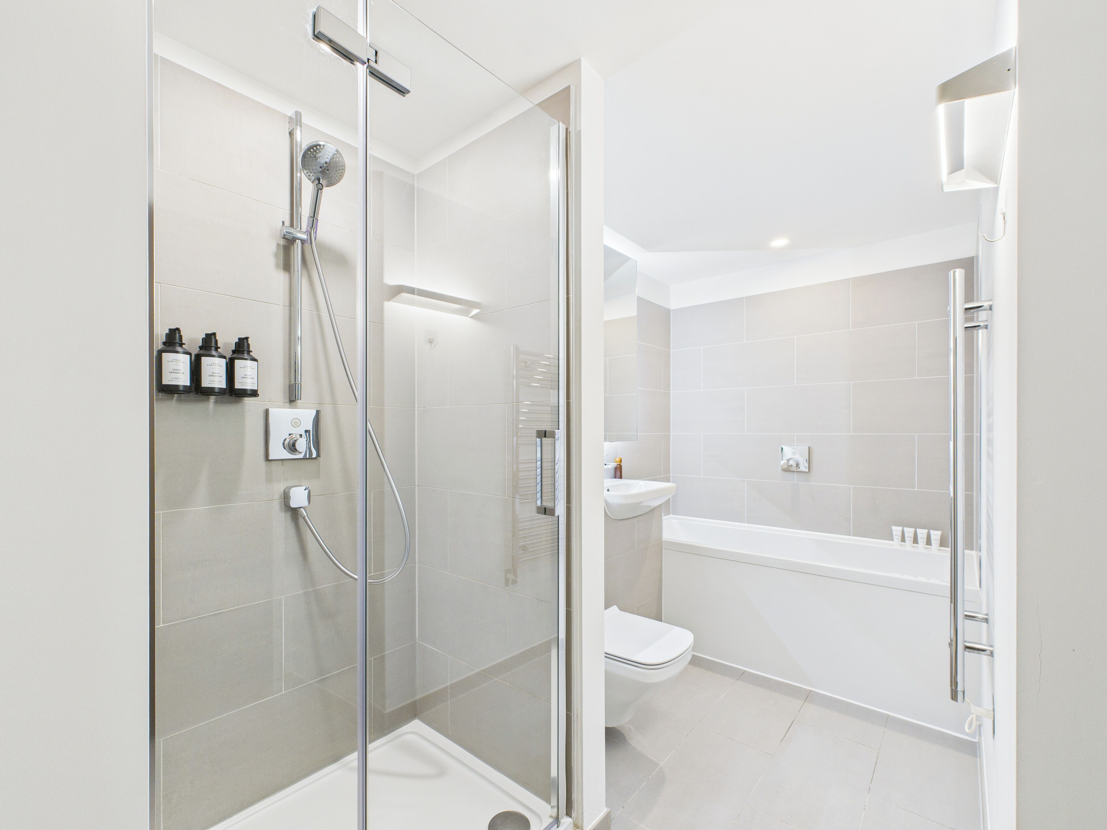 Un baño moderno con ducha de vidrio, inodoro blanco y bañera.
