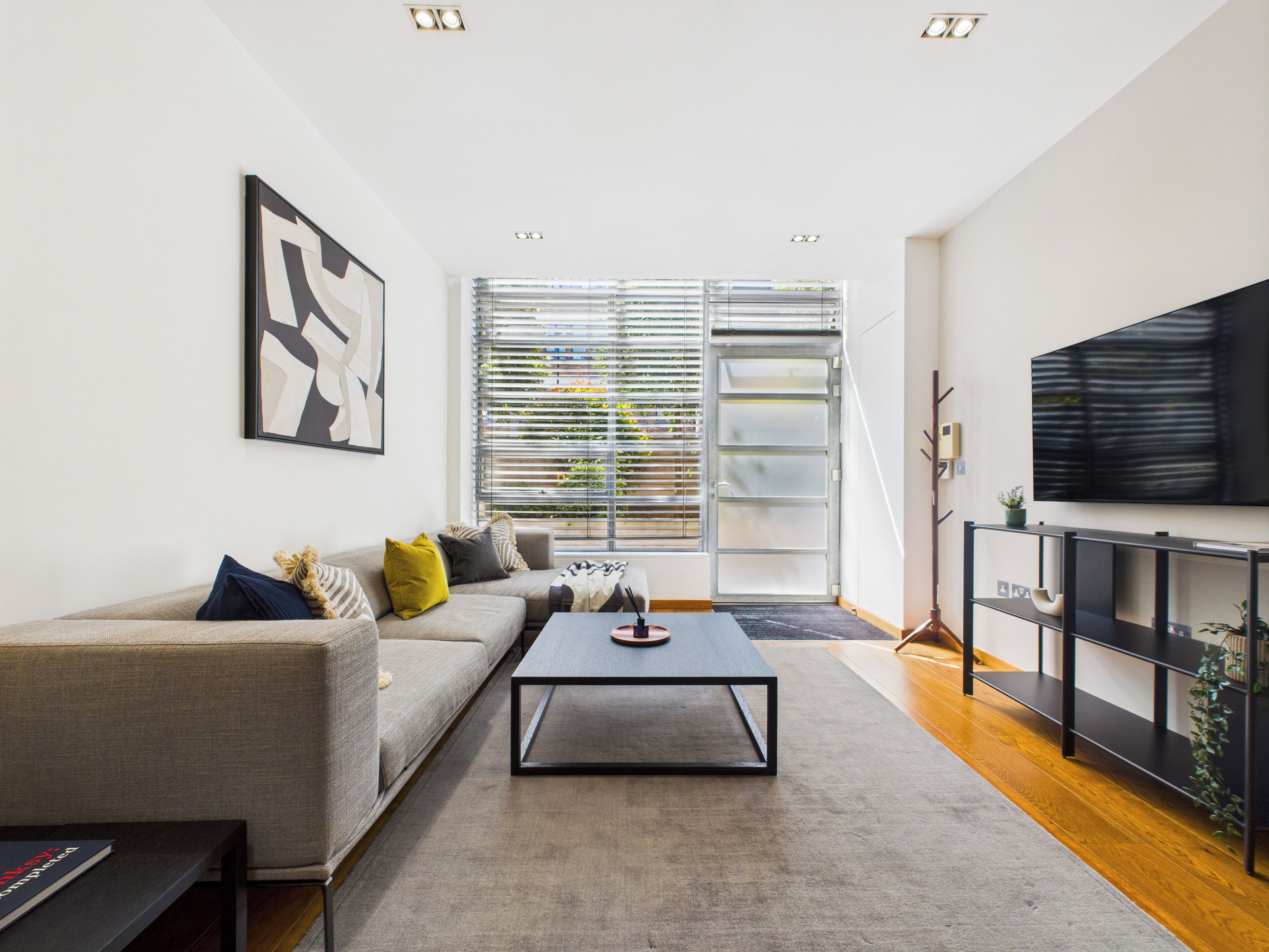 Un salon moderne avec un canapé, une table basse et un téléviseur fixé au mur.