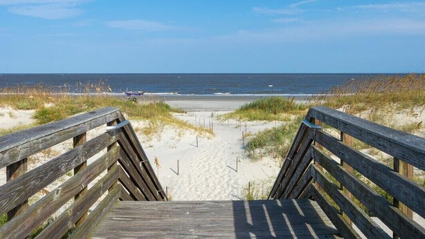 A wooden boardwalk leading to a beach with sand dunes and the ocean in the background. - Villa 407 - Beautiful 2 Bedroom Retreat (Jekyll Island)