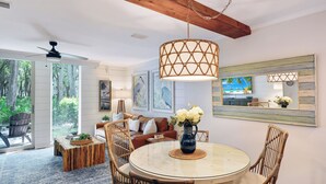 A dining area with a round table, wicker chairs, and a hanging light fixture. - Villa 407 - Beautiful 2 Bedroom Retreat (Jekyll Island)
