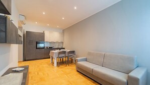 A modern apartment with a dining area, kitchenette, and a sofa. - Dimora Bassignano - Two Bedroom Apartment, Sleeps 5 (Cuneo)