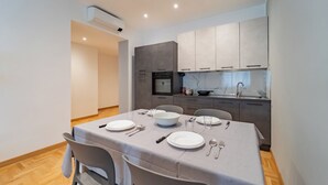 A modern kitchen with grey cabinets, a built-in oven, and a dining area with a table set for four. - Dimora Bassignano - Two Bedroom Apartment, Sleeps 5 (Cuneo)