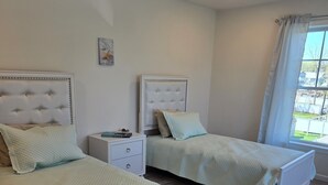 Un dormitorio con dos camas, una mesita de noche y una ventana con cortinas.