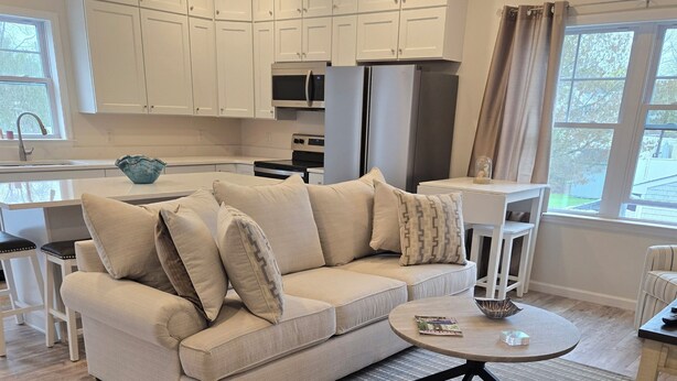 Una sala de estar moderna con un sofá color beige, un sillón a rayas y una mesa de centro redonda.